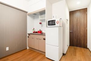 a kitchen with a white refrigerator and a microwave at RLiS-house Shin-Osaka Kita - Vacation STAY 9521 in Osaka