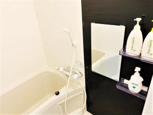 een badkamer met een bad, een toilet en een spiegel bij RLiS-house Shin-Osaka Kita - Vacation STAY 9525 in Osaka