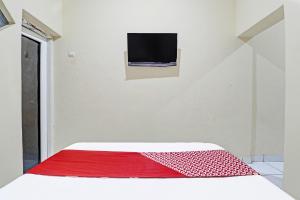 Sumedang的住宿－OYO Life 91480 Putridapisa Syariah，卧室配有红色和白色的床,墙上配有电视