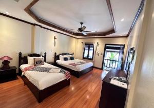 a bedroom with two beds and a ceiling fan at Y Not Lao Villa in Luang Prabang