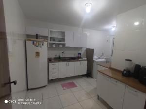 a white kitchen with a refrigerator and a sink at Apto Praia Inteiro Florestas das Gaivotas in Rio das Ostras