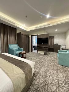 Al ‘AbābīdLophorina Hotel的酒店客房配有一张床、两把椅子和一台电视