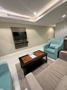 a living room with two blue chairs and a coffee table at Lophorina Hotel in Al ‘Abābīd