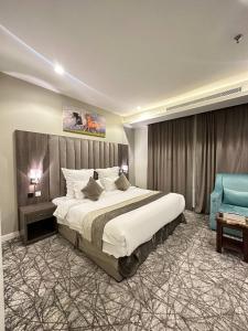 1 dormitorio con 1 cama grande y 1 silla azul en Lophorina Hotel en Al ‘Abābīd