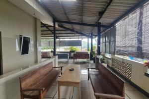 a room with benches and a table and windows at Capital O 93250 Hotel Tirta Kencana 2 Baturaden in Banyumas
