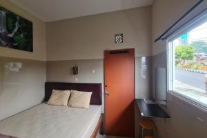 a small bedroom with a bed and a window at Capital O 93250 Hotel Tirta Kencana 2 Baturaden in Banyumas