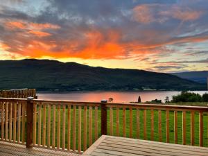 a wooden deck with a view of a lake at sunset at Black Grouse - Ukc6790 in Fort William