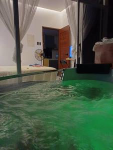 Bmf Homestay Jacuzzi في تاكلوبان: غرفة بها تجمع مياه أخضر بجانب سرير
