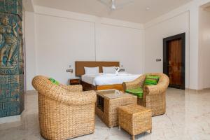 The Kaziranga Address في كازيرانغا: غرفة نوم مع سرير وكراسي الخوص وسرير