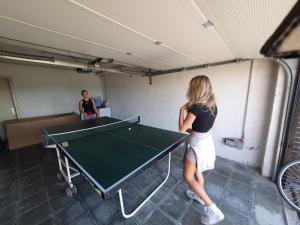 una donna in piedi accanto a un tavolo da ping pong di Vakantiehuis 't Leideveld a Maarkedal