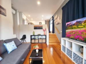 ein Wohnzimmer mit einem Sofa und einem TV in der Unterkunft Rosie Townhouse in prime location close to CBD in Melbourne
