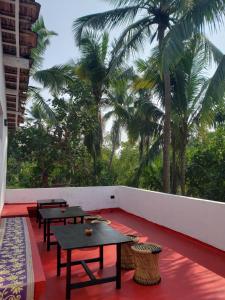 a row of tables on a balcony with palm trees at Adi Shakti Guesthouse in Querim