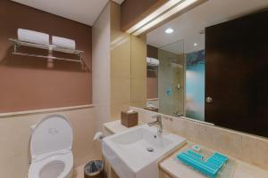 a bathroom with a toilet and a sink and a mirror at Grand Ixora Kuta Resort in Kuta