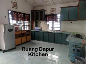 eine Küche mit grünen Schränken und einem Kühlschrank in der Unterkunft Dream Villa Homestay Kuala Nerang in Kuala Nerang