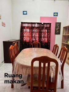 a dining room table with four chairs and a curtain at Dream Villa Homestay Kuala Nerang in Kuala Nerang