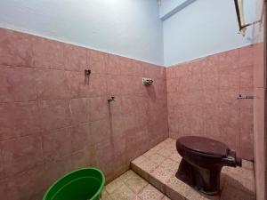 a bathroom with a toilet and a green bucket at OYO 93309 Mely Homestay in Kendari