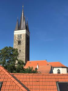 a clock tower with a steeple on top of roofs at Apartmán Pod Věží in Telč