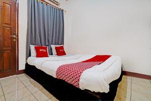 Un dormitorio con una cama con almohadas rojas y una ventana en OYO 93224 Fj Guest House, en Sayang