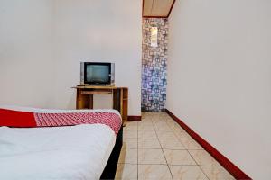 1 dormitorio con 1 cama y TV en una mesa en OYO 93224 Fj Guest House, en Sayang