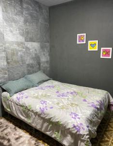 a bedroom with a bed with purple flowers on it at Casa em Freguesia (Jacarepaguá) in Rio de Janeiro