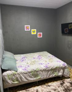 a bed in a bedroom with pictures on the wall at Casa em Freguesia (Jacarepaguá) in Rio de Janeiro