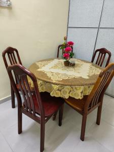 una mesa con dos sillas y un jarrón con flores. en Wafiy Homestay en Machang