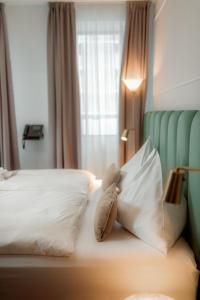 un osito de peluche sentado en una cama con almohadas en NED Hotel, en Graz