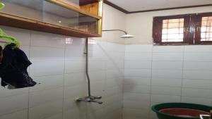a shower in a white tiled bathroom with a window at Nina Homes in Dar es Salaam