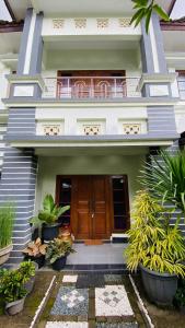 a house with a wooden door and some plants at Omah Najwa by Sampai Coliving in Kejayan