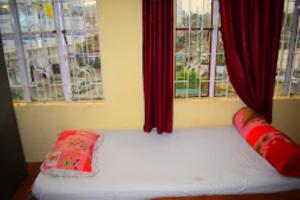 Bett in einem Zimmer mit roten Vorhängen und Fenstern in der Unterkunft Guwahati Lodge Guwahati in Guwahati