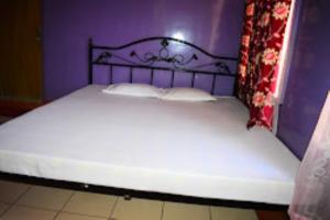 Bett in einem lila Zimmer mit einer großen Matratze in der Unterkunft Guwahati Lodge Guwahati in Guwahati