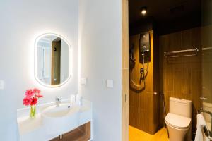 een badkamer met een wastafel, een toilet en een spiegel bij Emerald Hotel Residence in Phnom Penh