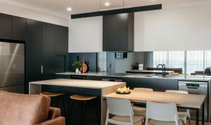 a kitchen with black cabinets and a wooden table at Met Apartments in Port Lincoln