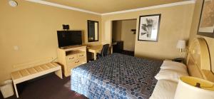 ein Hotelzimmer mit einem Bett und einem Flachbild-TV in der Unterkunft Heritage Inn in Milpitas