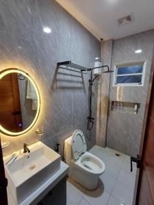 a bathroom with a sink and a toilet and a mirror at Bmf Homestay Jacuzzi in Tacloban