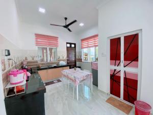 a kitchen with a table and a red sliding door at Roomstay HELLOKITTY HOUSE in Kuala Terengganu