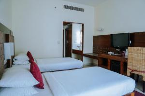 a hotel room with two beds and a television at Devaragam in Guruvāyūr