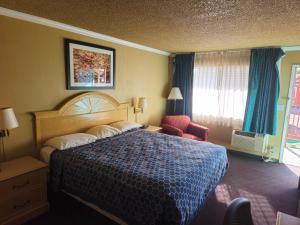 a hotel room with a bed and a chair at Heritage Inn in Milpitas