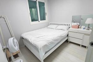 a small white bedroom with a bed and a window at Roy Stay Suwon Haenggung in Suwon