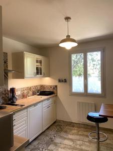 a kitchen with white cabinets and a table and a window at Charmante Maison au pied du Luberon in Cheval-Blanc