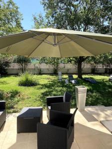 a patio with an umbrella and chairs and tables at Charmante Maison au pied du Luberon in Cheval-Blanc +13 photos