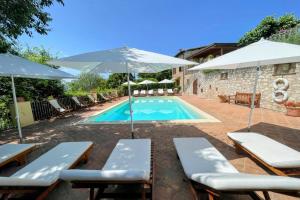 - une piscine avec des chaises longues et des parasols dans l'établissement Spoleto Country Park - Slps 28, à Acquaiura
