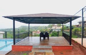 een paviljoen met een tafel en stoelen eronder naast een zwembad bij Colorbar Villa in Mahabaleshwar