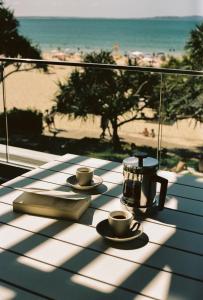 una mesa con dos tazas y un libro sobre una mesa con la playa en 71 Hastings Street - Beachfront, en Noosa Heads 148 fotos más