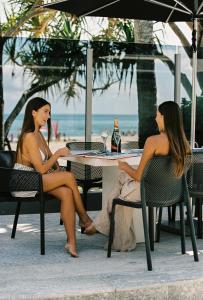ヌーサヘッズにある71 Hastings Street - Beachfrontの二人の女性が海辺のテーブルに座っている