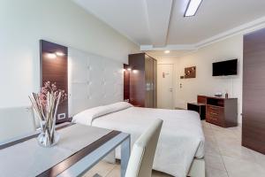 1 dormitorio con cama, mesa y TV en Hotel Residence Le Dune breakfast included, en Lido Adriano