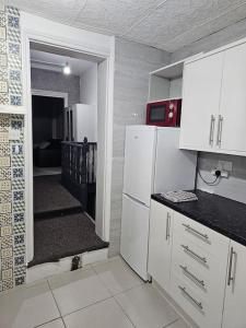 een keuken met witte kasten en een hal met een trap bij London Serviced Accommodation E10 x DM 4 Weekly x Monthly Offers x Leyton x by D6ten Homes Ltd in Londen