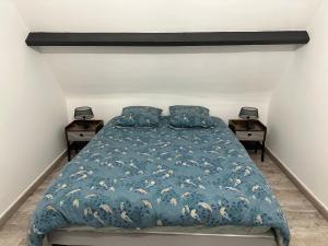 a bedroom with a bed with a blue comforter at Escapade entre Terre et Mer in Guilmécourt
