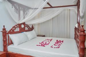 a bedroom with a bed with pink flowers on it at Beach Way Villa in Malindi