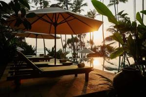 a lounge chair with an umbrella and a table at Eraeliya Villas & Gardens in Weligama